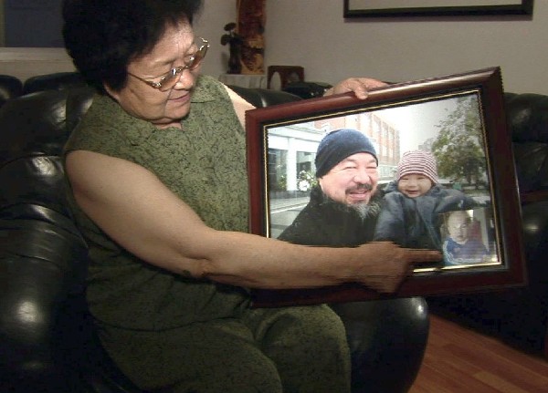 La madre del creador chino y disidente Ai Weiwei, la poetisa Gao Ying, posa con un retrato de su hijo.