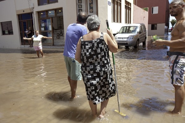 Habitantes del barrio pesquero de San Andrés, en Santa Cruz de Tenerife, tratan de achicar el agua que ha inundado sus calles a causa del fuerte oleaje que ha dejado desperfectos en cinco viviendas.