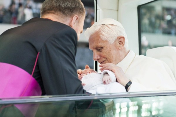 El papa Benedicto XVI bendice a un bebé en el papamóvil.