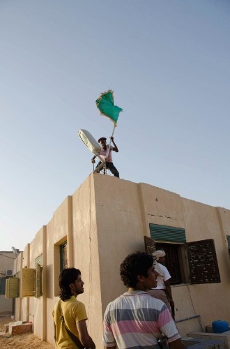 Rebeldes libios quitan una bandera del régimen de Gadafi del tejado de una vivienda en la ciudad de Sebha.