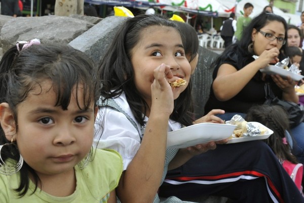 Una niña degusta una porción del taco.