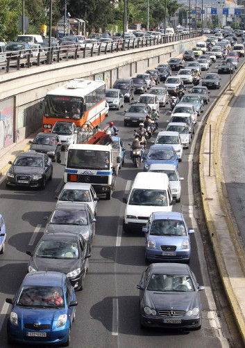 Una larga fila de vehículos y motos permanecen detenidos en una importante carretera de Atenas.