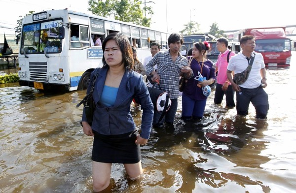 Tailandeses van a su trabajo por las calles inundadas de Bangkok.