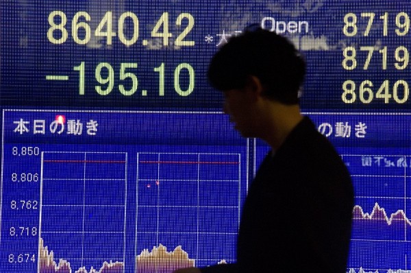 Un ejecutivo japonés camina frente a un tablero electrónico con los resultados de la Bolsa de Tokio.