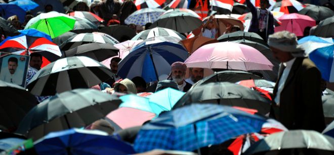 Manifestantes yemeníes se protegen del sol con paraguas.