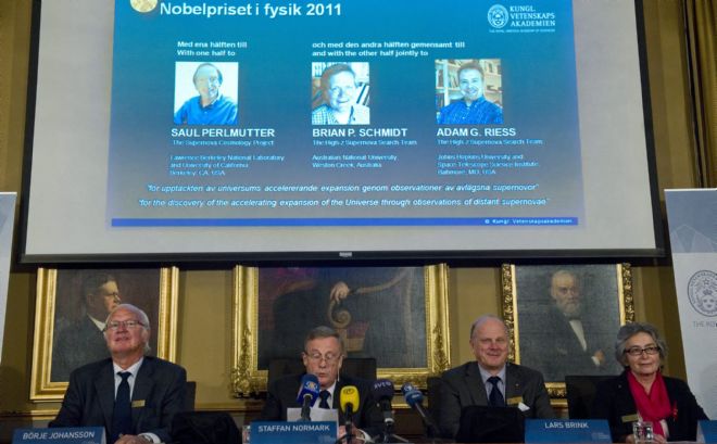 (Iz a der) Los miembros del comité de premios de la Real Academia de Ciencias de Suecia Borje Johansson, Staffan Normark, Lars Brink y Olga Botner ante una pantalla que muestra a los tres galardonados con el Premio Nobel de Física 2011.