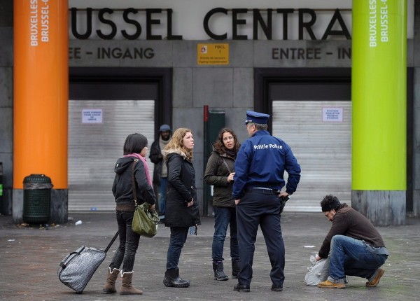 Viajeros conversan con un policía delante de la puerta cerrada de la Estación Central de Bruselas.