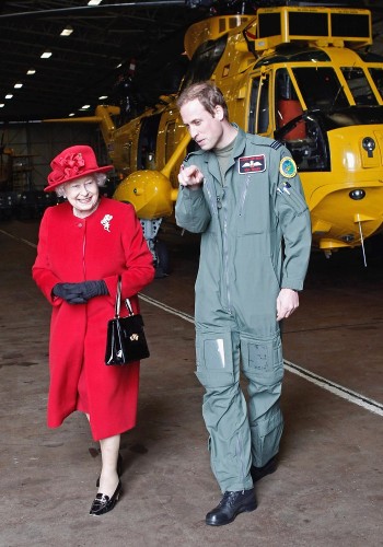 El príncipe Guillermo mientras muestra a su abuela, la reina Isabel II de Inglaterra (izq), el hangar donde se guarda el helicóptero en el que realiza las prácticas como piloto de búsqueda y rescate.