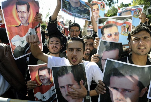 Jóvenes libios simpatizantes del presidente sirio, Bacharl Al Assad, muestran carteles con su fotografía.