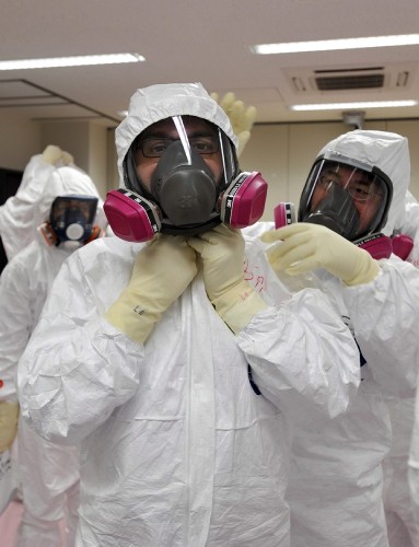 Un periodista es ayudado por un trabajador de TEPCO a colocarse el traje de seguridad para visitar la central nuclear de Fukushima Daiichi.