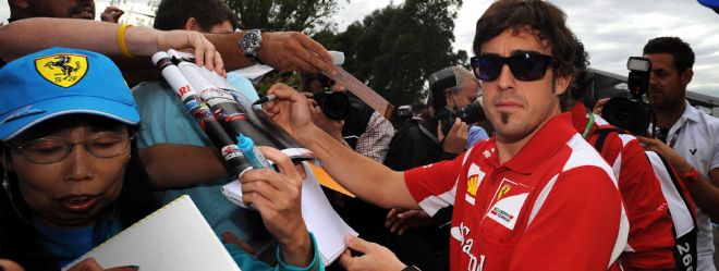 El piloto español Fernando Alonso (d), de Ferrari, firma autógrafos.