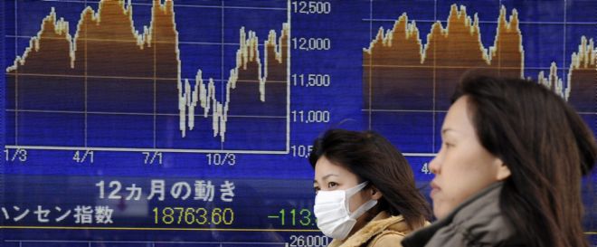 Dos mujeres pasan por delante de una pantalla electrónica con los resultados del cierre de la Bolsa de Tokio.