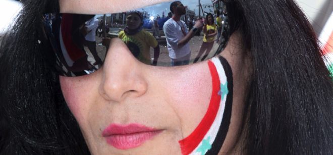 Una manifestante progubernamental con los colores de la bandera siria pintada en la cara.