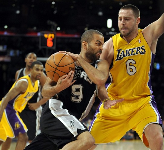 Josh McRoberts (d) de Los Angeles Lakers defiende un ataque de Tony Parker.