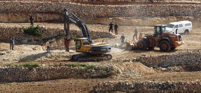 Dos excavadoras del ejército israelí destruyen una reserva de agua usada por granjeros palestinos en las afueras de Hebrón.