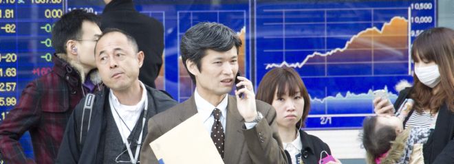 Japoneses pasan por delante de una pantalla con el cierre de la Bolsa de Tokio.