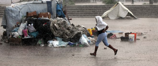 Una mujer corre bajo una intensa lluvia en el campo de refugiados en Champ de Mars, en Puerto Príncipe.