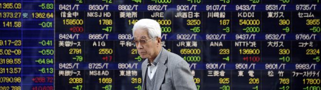 Un hombre camina frente a un tablero electrónico que indica los resultados de la Bolsa de Tokio.