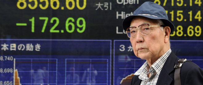 Un viandante pasa delante de una pantalla que indica el valor alcanzado por el índice Nikkei en Tokio.