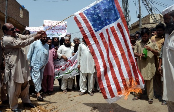Varias personas queman una bandera estadounidense durante una manifestación contra Estados Unidos.