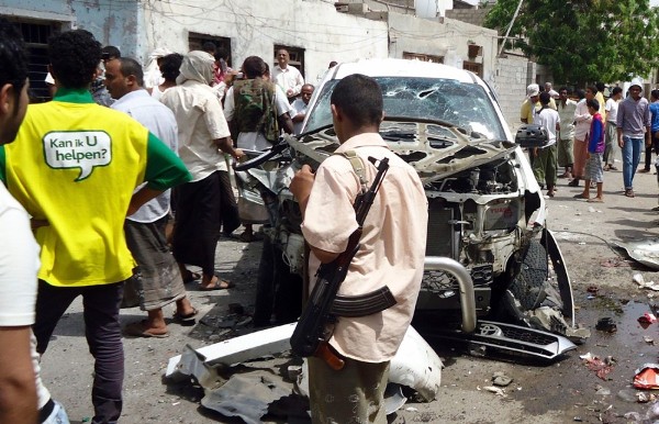 Varios curiosos congregados alrededor de un vehículo destruido tras el atentado suicida contra el general Salem Qatan.