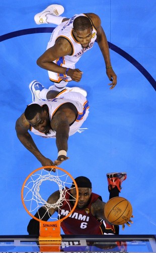 El jugador de Heat LeBron James (frente) busca la cesta ante Kendrick Perkins.