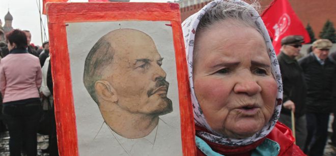 Una mujer sostiene una imagen de Vladimir Lenin, líder de la revolución rusa.