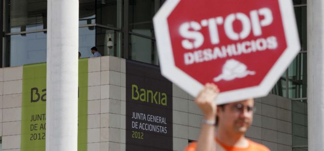 Un hombre sujeta un cartel en protesta por los deshaucios a las afueras del Palacio de Congresos de Valencia.