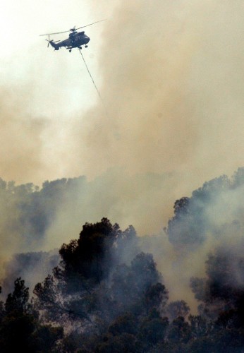 Un helicóptero descarga agua sobre el fuego durante los trabajos de extinción del incendio de los alrededores de Alcublas y Liria.