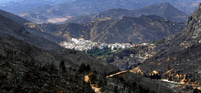 Vista general del pueblo de Dos Aguas rodeado de monte quemado, arrasado por el grave incendio.