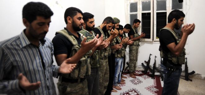 Rebeldes sirios oran dentro de la base militar Tecvid Sicco, al norte de la ciudad de Alepo.