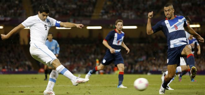 El jugador de Uruguay Luis Suarez (izq.) chuta a portería en el partido entre Reino Unido vs Uruguay en los Juegos Olímpicos de Londres 2012.