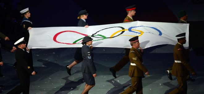 La bandera olímpica es transportada por militares.