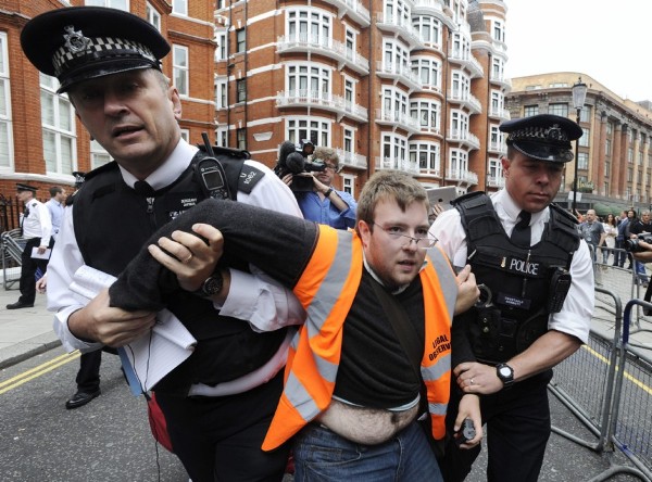 Policías británicos retiran de la zona frente a la embajada de Ecuador a un simpatizante de Julian Assange.