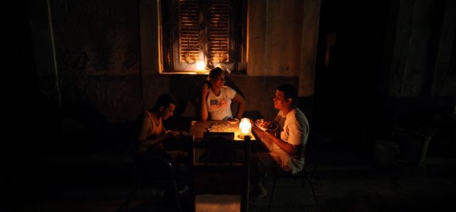 Varias personas comen en una calle sin iluminación en La Habana (Cuba).