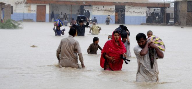 Una familia se abre paso con el agua casi por la cintura en una calle inundada de Jafarabad, Pakistán.