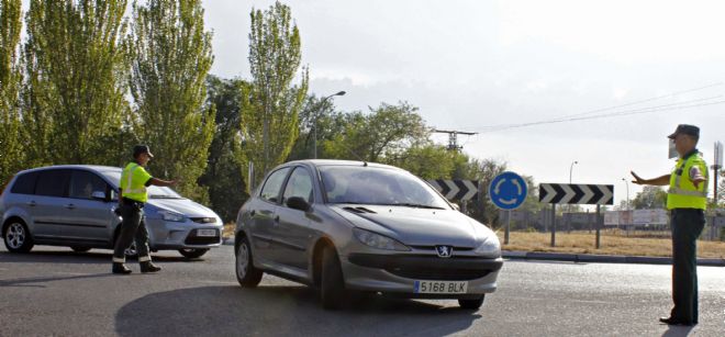 Dos agentes paran a dos vehículos en una vía madrileña dentro de las medidas tomadas por la Dirección General de Tráfico (DGT).