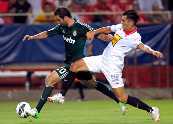 El delantero argentino del Real Madrid, Gonzalo Higuaín, intenta marcharse del defensa bosnio del Sevilla, Emir Spahic.