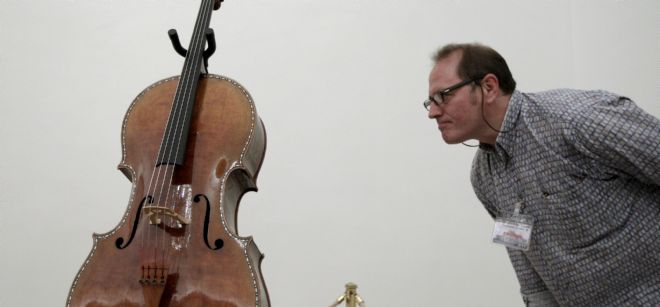 Un hombre observa de cerca el recién restaurado Violonchelo (nº de inventario 10076033) del Cuarteto Stradivarius de la Colección Real.