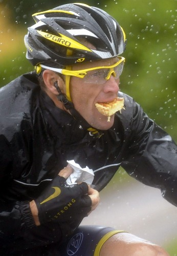 Lance Armstrong come mientras compite bajo la lluvia durante una etapa del Tour de France.