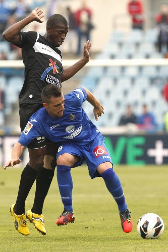 El delantero del Getafe, Paco Alcácer (d), intenta controlar el balón ante el centrocampista senegalés del Levante, Pape Diop (i).