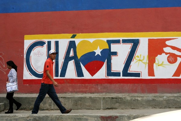 Un hombre camina frente una pared pintada con referencia al presidente Venezolano Hugo Chávez.