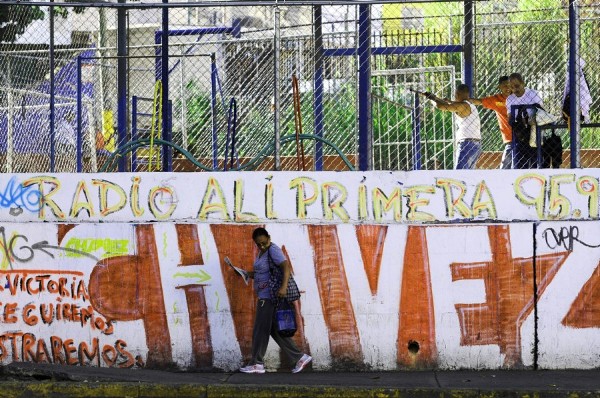 Una mujer camina frente a un muro pintado con un mensaje alusivo al presidente Hugo Chávez.