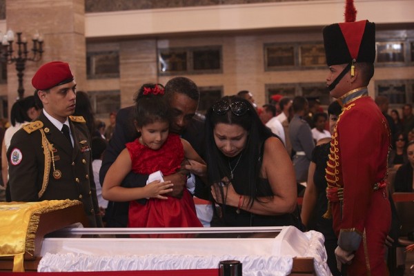Fotografía cedida por la presidencia de Venezuela muestra a una niña y su familia observando el cuerpo del gobernante de Venezuela, Hugo Chávez.