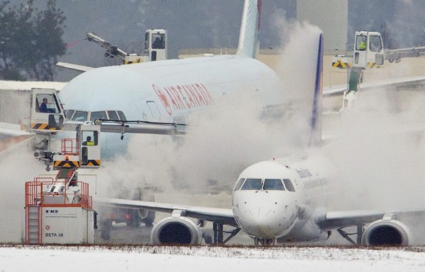 Varios operarios eliminan la escarcha acumulada en el fuselaje de un avión en el aeropuerto de Fráncfort (Alemania).