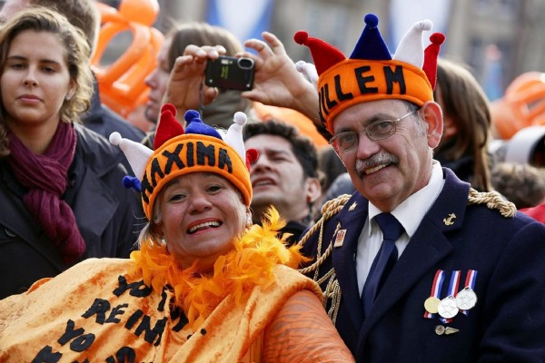 Una mujer y un hombre lucen dos coronas naranjas con los nombres de Máxima y Guillermo en la plaza Dam en Ámsterdam (Holanda) hoy, martes 30 de abril de 2013. 