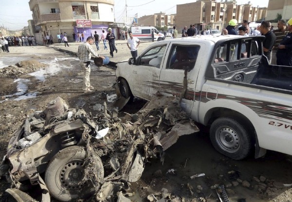 Varios iraquíes inspeccionan el escenario de un ataque con coche bomba en Kirkuk, al norte de Irak.