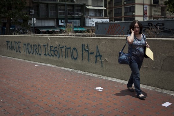 Una mujer camina junto a un muro con una pintada escrita en protesta contra del resultado de las elecciones que dieron como ganador al presidente venezolano, Nicolás Maduro, el, miércoles 17 de abril de 2013, en Caracas (Venezuela).