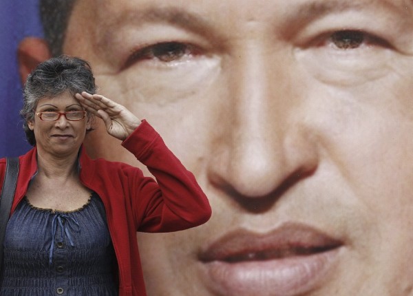 Una mujer saluda ante una fotografía del fallecido presidente de Venezuela Hugo Chávez.