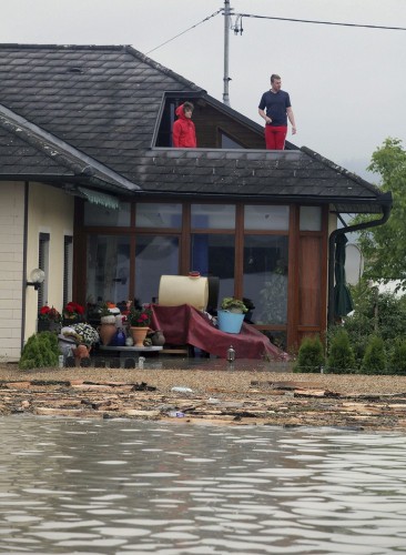 Una pareja observa desde la terraza de su vivienda tras quedar aislados debido a las inundaciones que afectaron a la localidad de Walding.